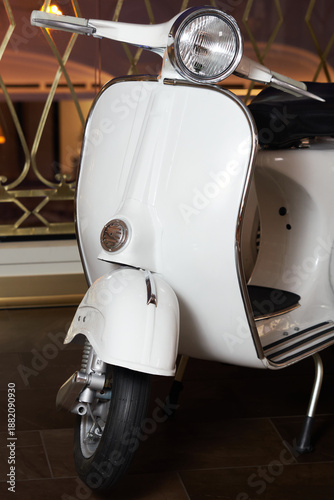 White scooter parked indoors on a dark floor with a blurred ornate background