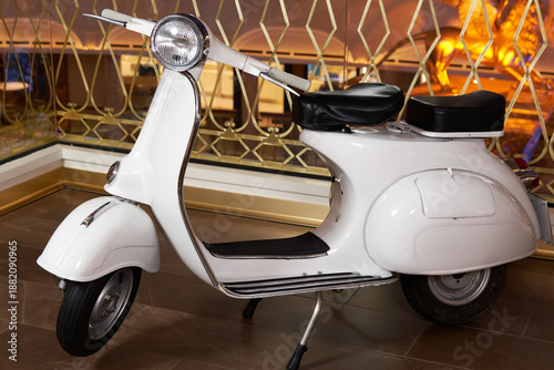 White scooter parked indoors on a tiled floor in front of a golden decorative screen