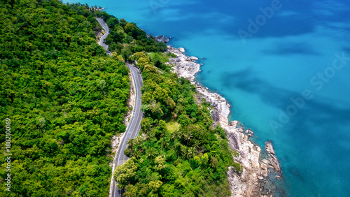 Aerial view of road between coconut palm tree and great ocean at daytime in Nakhon Si Thammarat, Thailand