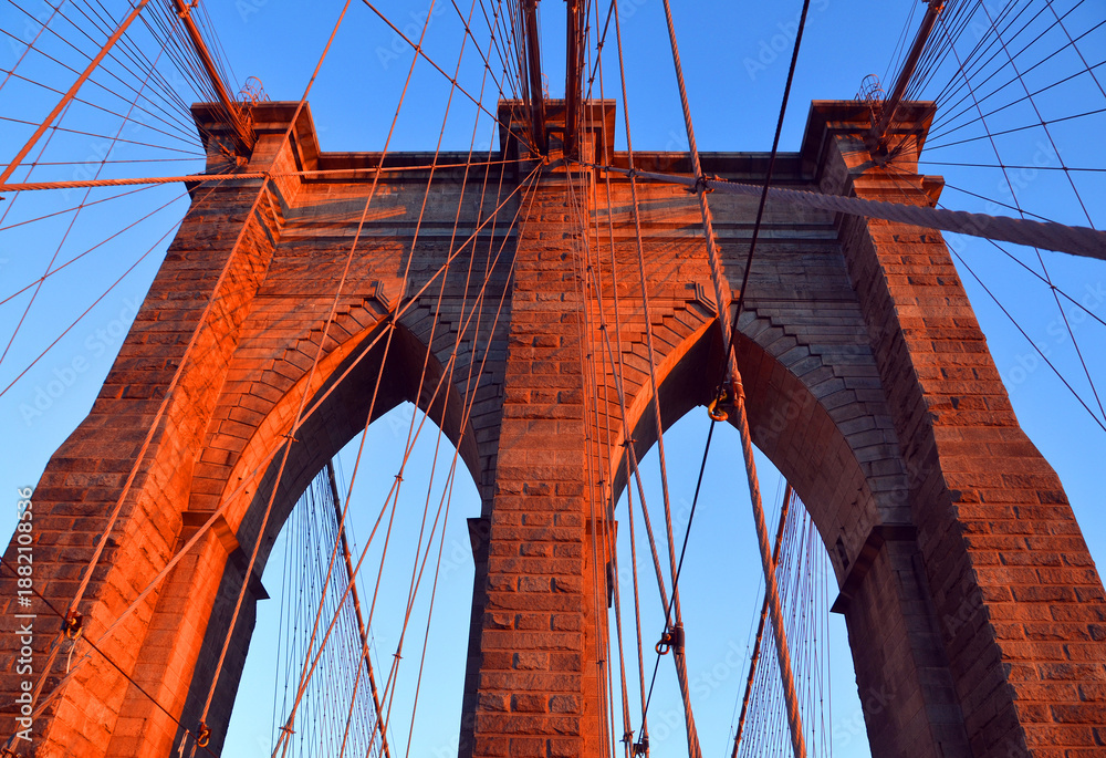 Obraz premium The Brooklyn Bridge is one of the oldest suspension bridges in the United States. Completed in 1883, it connects the New York City boroughs of Manhattan and Brooklyn by spanning the East River.