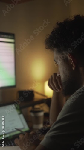Stressed man working late at night on laptop in a dimly lit room