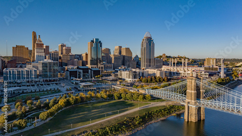 Aerial view of the majestic John A. Roebling Suspension Bridge, its stone towers anchoring the skyline against the vibrant city, Covington, Kentucky, United States.