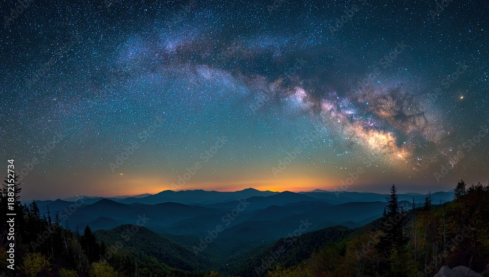 Fototapeta premium Vast, starry night sky arches over silhouetted mountain ranges