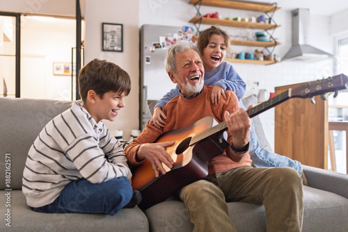 Bild auf Leinwand Grandfather Playing Guitar and Singing with Grandchildren