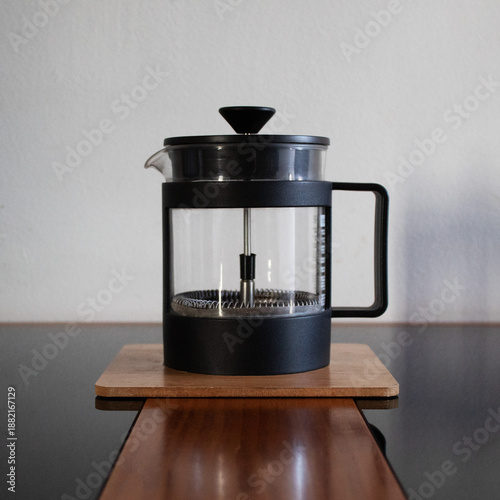 French press coffee maker on a board on the table