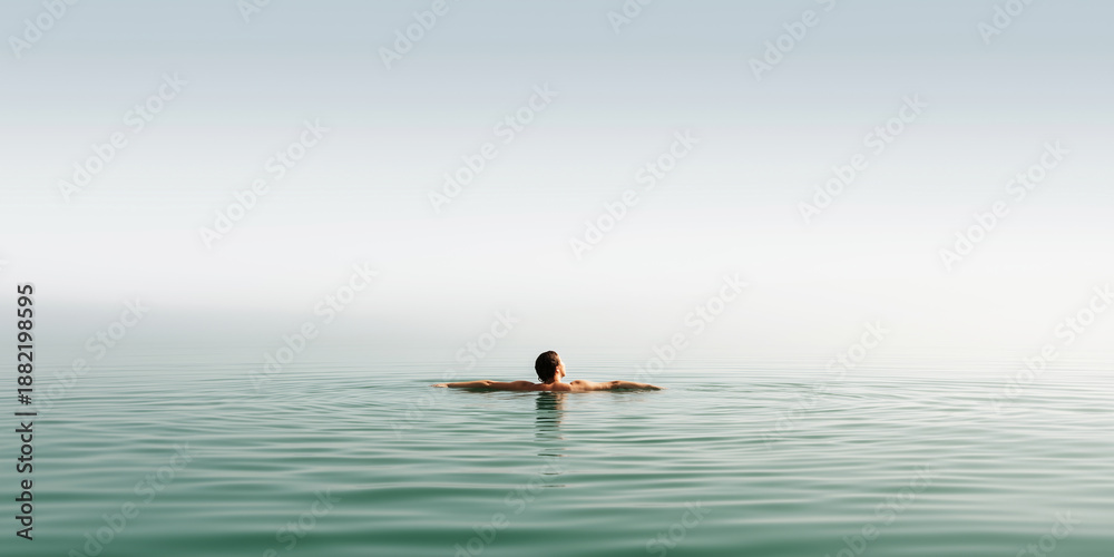 Fototapeta premium Person floating on back in calm open water finding peace, relaxation, and embracing solitude under a clear sky