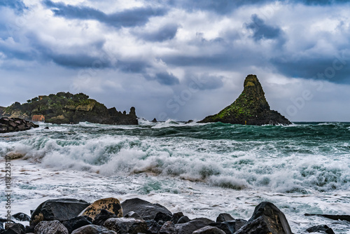 Fotografia Dramatic coastal scene featuring rough waves crashing against dark volcanic rocks in Sicily