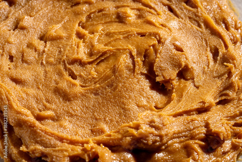 Creamy peanut butter texture background with smooth swirls and natural organic appearance. Ideal for food packaging, healthy lifestyle concepts, vegan and plant-based nutrition, cooking, baking
