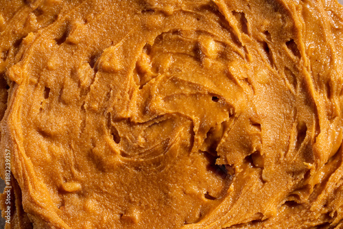 Creamy peanut butter texture background with smooth swirls and natural organic appearance. Ideal for food packaging, healthy lifestyle concepts, vegan and plant-based nutrition, cooking, baking