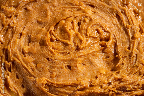 Creamy peanut butter texture background with smooth swirls and natural organic appearance. Ideal for food packaging, healthy lifestyle concepts, vegan and plant-based nutrition, cooking, baking