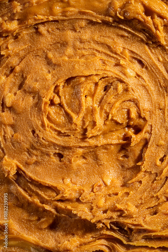 Creamy peanut butter texture background with smooth swirls and natural organic appearance. Ideal for food packaging, healthy lifestyle concepts, vegan and plant-based nutrition, cooking, baking