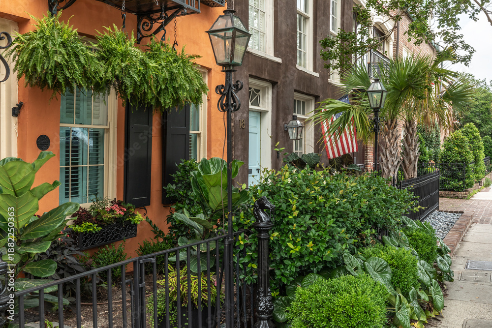 Naklejka premium Charleston, South Carolina, USA - May 27, 2025: Colorful Historic Homes with Gas Lamps and Lush Gardens on Adgers Wharf street in Historic Charleston