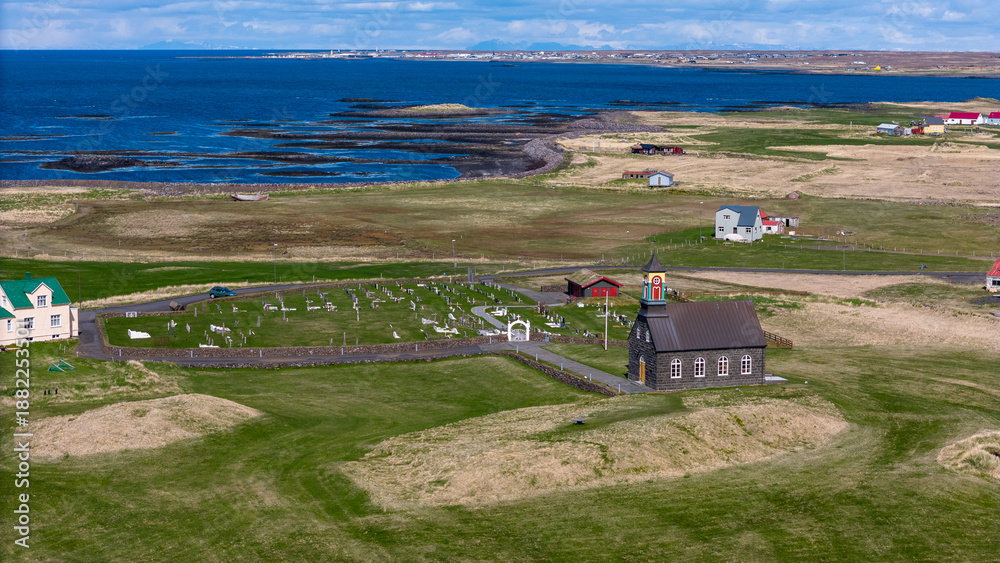 Fototapeta premium Aerial drone view of Hvalsneskirkja church on the Reykjanes Peninsula in Iceland. The historic stone church stands near the rugged Atlantic coastline, surrounded by lava fields and dramatic Nordic lan