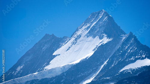 Tablou pe pânză Close up scenic view of a jagged snow capped mountain peak against a blue sky in Grindelwald, Switzerland
