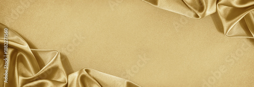 Light soft golden silk satin. Shiny silky fabric. Wavy folds. Draped. Elegant luxury background. Empty blank space template design ad. Christmas festive birthday. Flat lay, top view table.Wide banner.