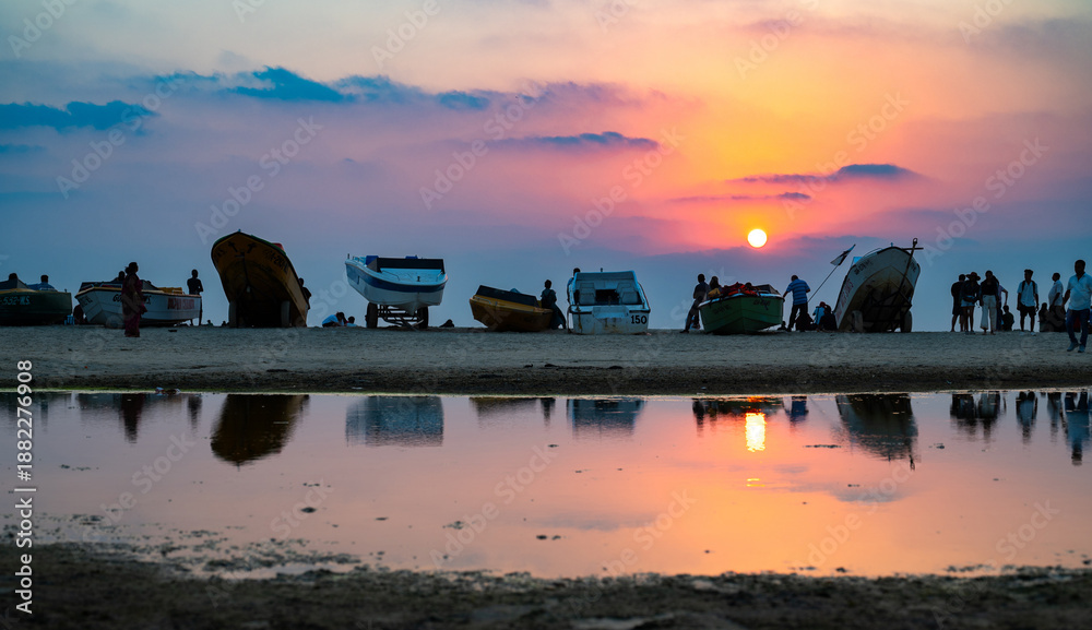 Fototapeta premium Sunset at Colva Goa beach in South India, silhouette of boats and people, tropical west coast, Arabian Sea in Asia, vacation destination