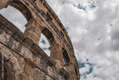 Tableau sur toile Porzione dell’anfiteatro romano di Pola, con il cielo nuvoloso sullo sfondo, evidenziando la maestosità delle antiche pietre e l’architettura storica