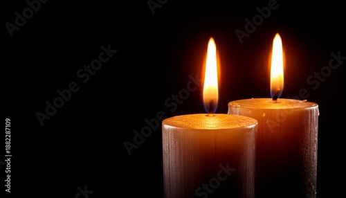 warm glow of two melting candles on black background for in memoriam tribute