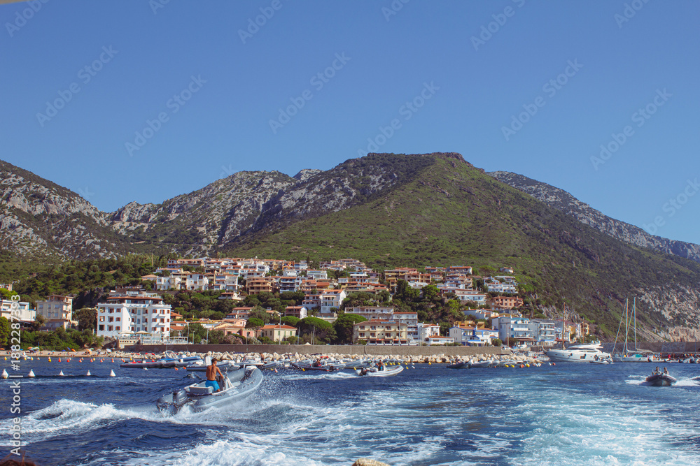 Fototapeta premium Veduta di Cala Gonone dalla barca. Mare e paesaggio collinare con paese sullo sfondo. Estate.