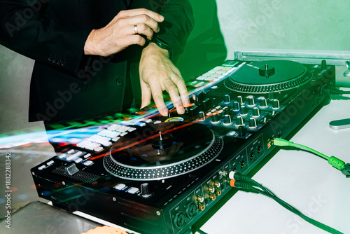 Photo of a DJ's hands switching music during a performance on the console. Musical accompaniment for discos and parties