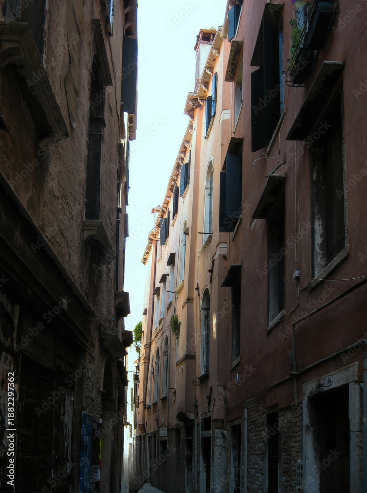 Fototapeta premium Narrow alleyway in Venice with charming pastel buildings and sunlight
