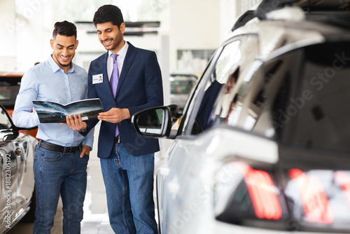 Quadro em tela Middle-eastern guy having conversation with sales assistant in auto showroom