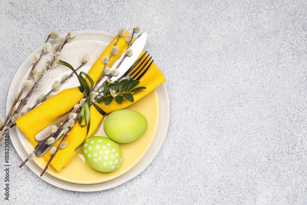 Obraz premium Festive table setting with Easter eggs and willow branches on light background, top view. Space for text