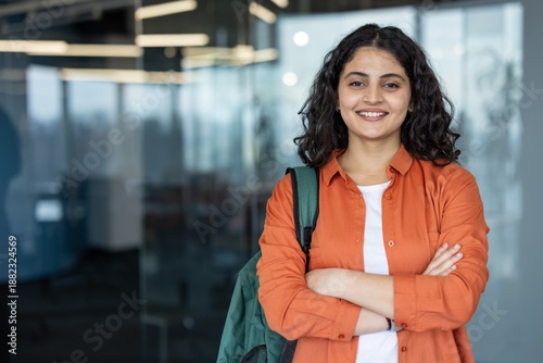 Photography Young indian woman with a backpack smiling confidently, posing with crossed arms