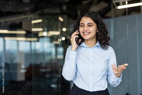 Billede på lærred Indian businesswoman standing in a modern office, enjoying a pleasant conversati
