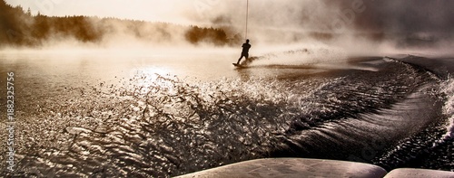 Tableau sur toile A person is wakeboarding on a lake during sunset