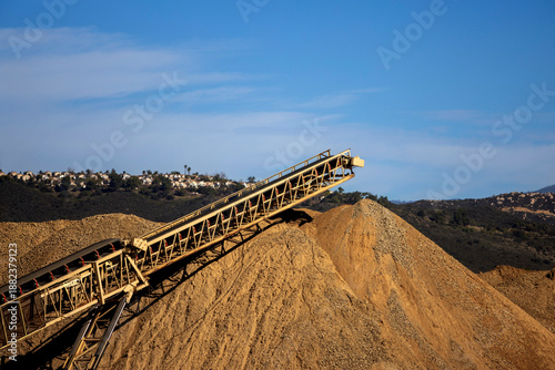 Billede på lærred A conveyor machine and a large mound of dirt and gravel at a construction site