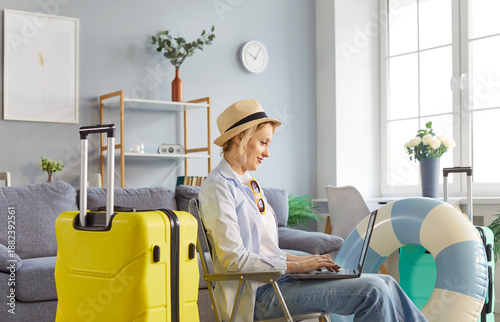 Tableau sur toile Happy woman planing summer vacation trip, booking online with laptop at home living room, focusing on travel in a cozy setting with engagement and excitement during the preparation process