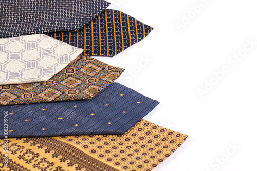 Assortment of men's neckties with different patterns isolated on a white background. Fashion accessories arranged diagonally with ample copy space for design.