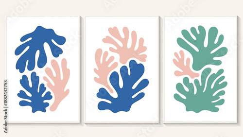 Three white canvases display stylized coral illustrations in blue, pink, and green hues, arranged side by side on a light beige surface from a frontal viewpoint.