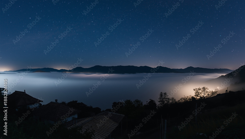 Naklejka premium 星が薄れゆく未明、月光の銀に染まる雲海と黒い屋根が連なる静寂の谷、人物なし