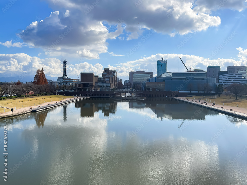 Fototapeta premium 富岩運河環水公園から見た、富山県富山市の街並み。水面に空が反射して美しい冬の風景。