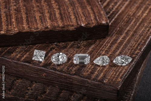 Foto Row of loose cut diamonds in different shapes displayed on a rustic wooden surface, highlighting variety, brilliance, and fine gemstone craftsmanship