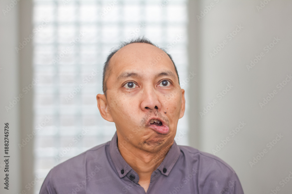 Fototapeta premium Surprised Asian adult man looking upward with shocked facial expression