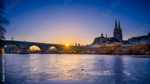 Sunrise over Stone Bridge in Regensburg, Bavaria, Germany in winter with frozen Danube
