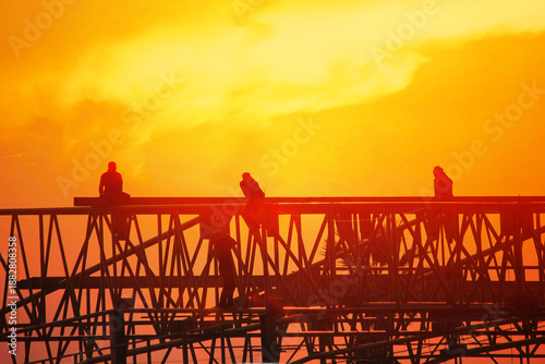 group of worker work late wilding steel structure in construction site on sun set abstract nature background