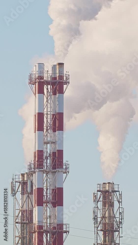 Thermal power plant pipes with vapor rising to the sky. Vapor rising in front of the blue sunny sky.