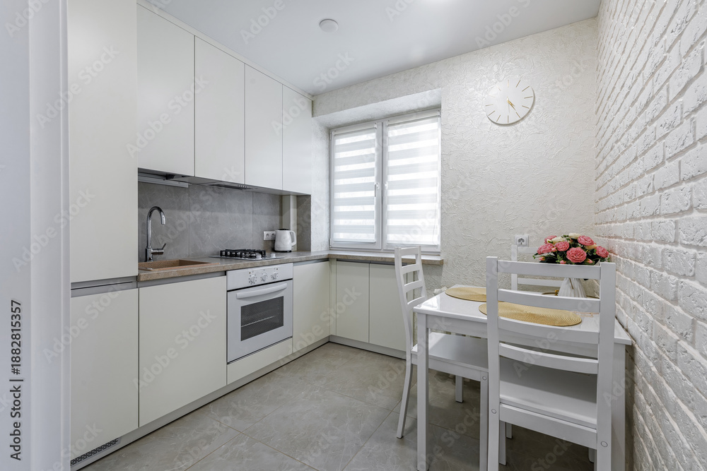 Fototapeta premium Bright modern kitchen and dining area with white furniture