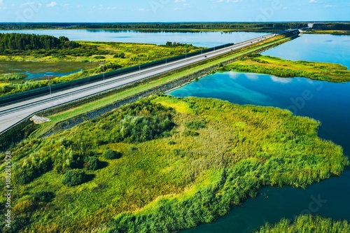 Fényképezés A Scenic Overhead View of a Highway Bordering a Serene River Amidst Lush Greener