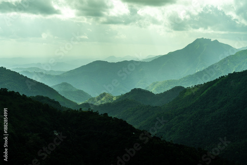 The mountains are covered in lush green trees and the sky is cloudy
