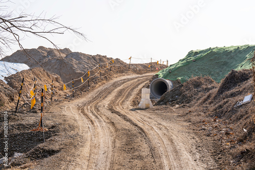 construction site with dirt road and barren land under clear sky, showing early stage infrastructure development and wide open space for future projects.