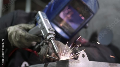 Welder performing manual laser welding with sparks in workshop