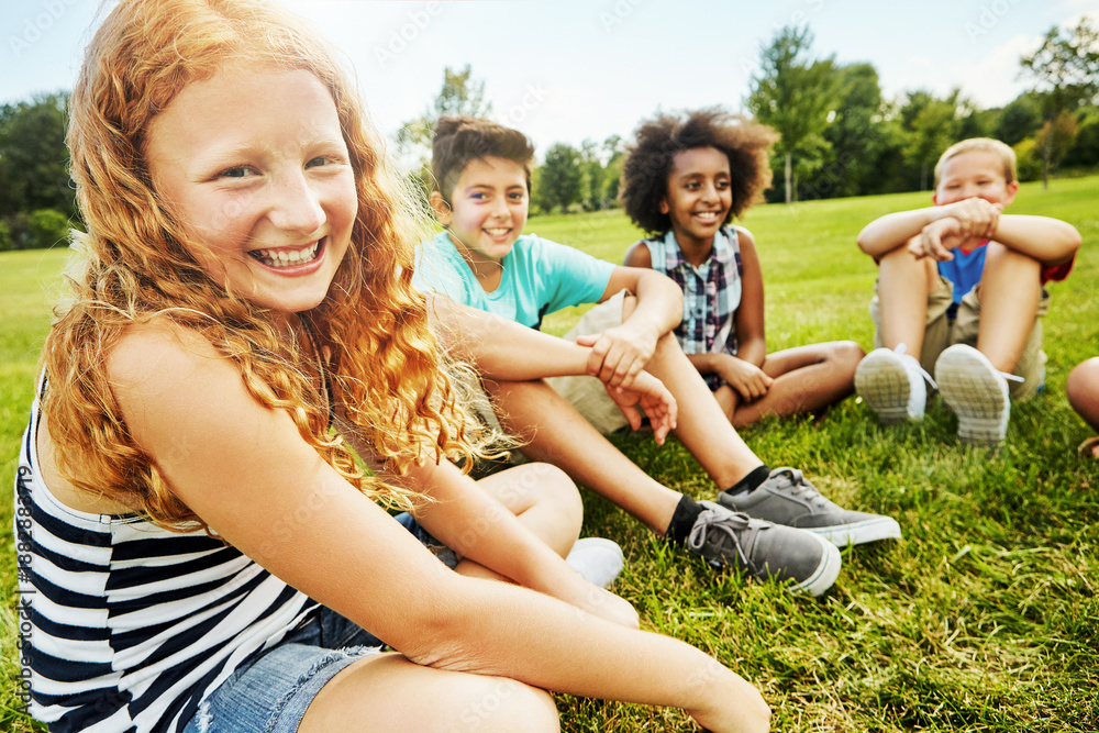 Fototapeta premium Happy, children and portrait of girl outdoor for playing, bonding and connection on grass. Childhood, laughing and kid with friends in park for summer holiday, weekend and relax together for fun