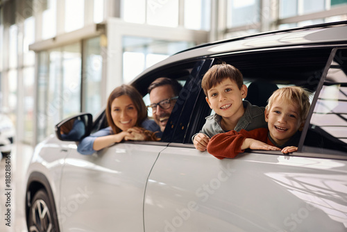 Happy family buying new car in auto salon.