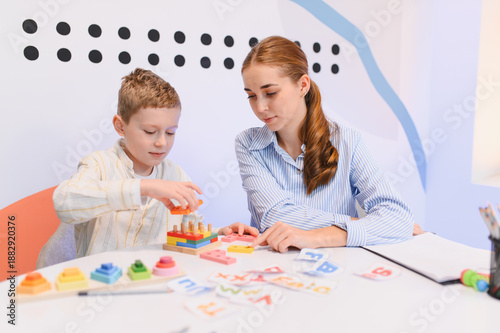 Konstfotografi Boy learning fine motor skills with tutor in classroom
