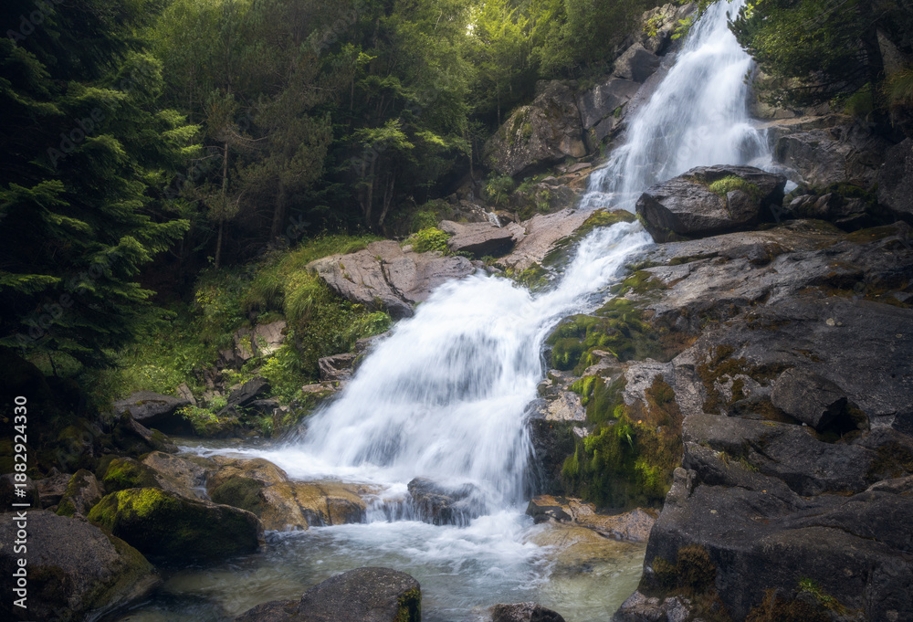 Fototapeta premium Molieres waterfall cascades through lush greenery in Vall d'Aran, Catalonia